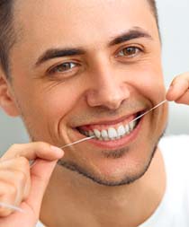 man flossing his replacement teeth as instructed by an implant dentist in Gilbert