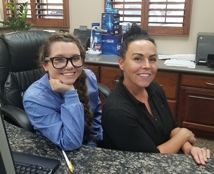 Two smiling dental office team members