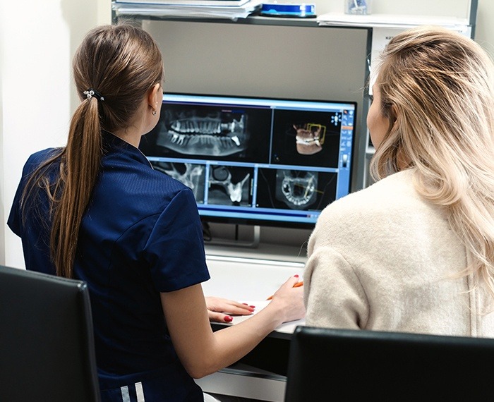 Two dental team members looking at digital x-rays