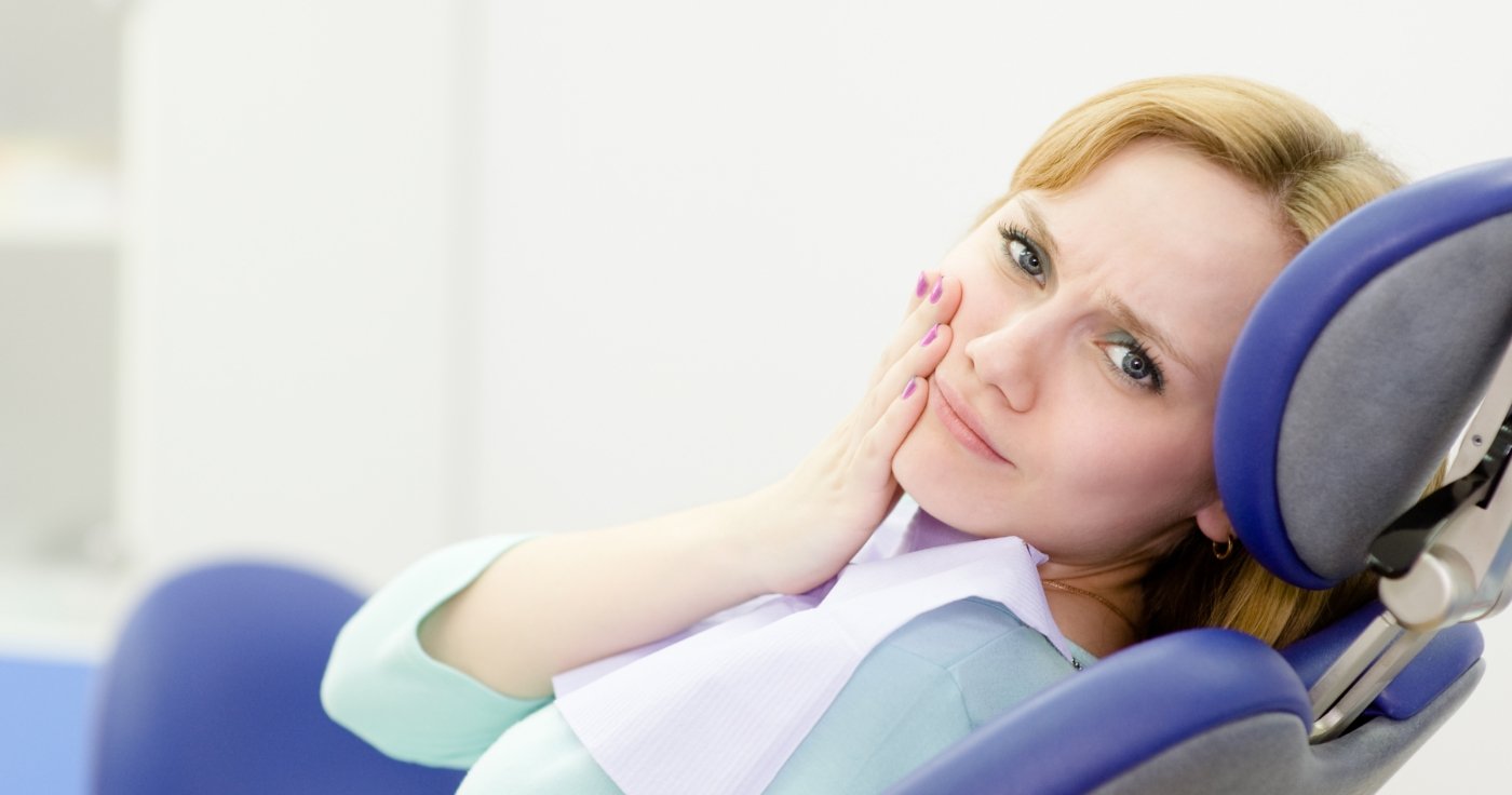 Woman in need of emergency dentistry holding cheek in pain