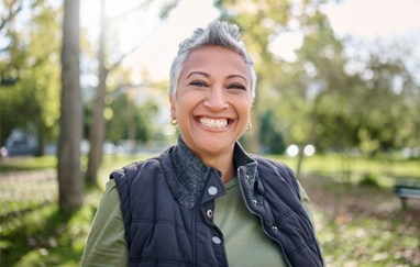 Senior woman with vest standing outside and smiling