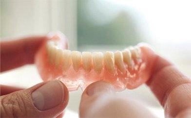 Close-up of hands holding dentures in Gilbert, AZ