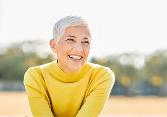 Senior woman with yellow shirt sitting outside and smiling