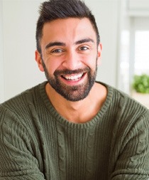 Man in green sweater sitting at home and smiling