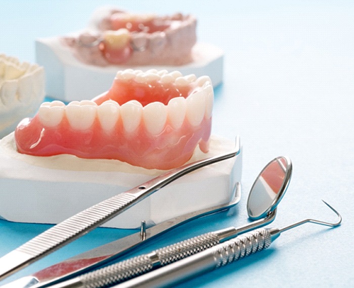 Models of dentures lying next to dental tools