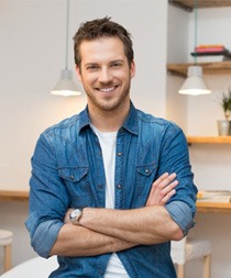 Man standing in a room smiling with arms folded