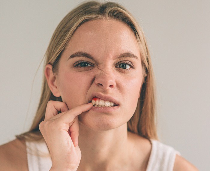 Woman in need of periodontal therapy pointing to inflamed gum tissue
