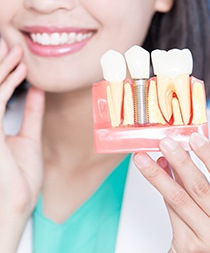 An up-close look at a dentist holding a cross-section mouth mold that contains a single dental implant between two healthy teeth