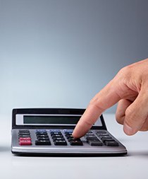 A person pushing numbers on a calculator and a model of a tooth