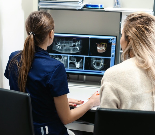 Two dental team members looking at digital x rays