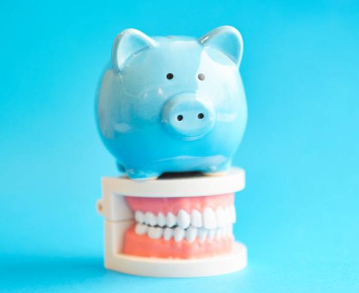 blue piggy bank sitting on top of a set of dentures 