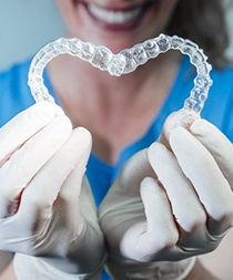 Invisalign dentist in Gilbert holding two clear aligners in the shape of a heart 