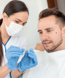 A dentist showing a patient an Invisalign aligner