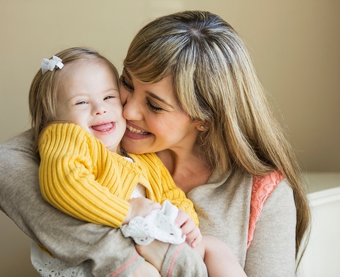 Mother hugging smiling toddler during special needs dentistry visit