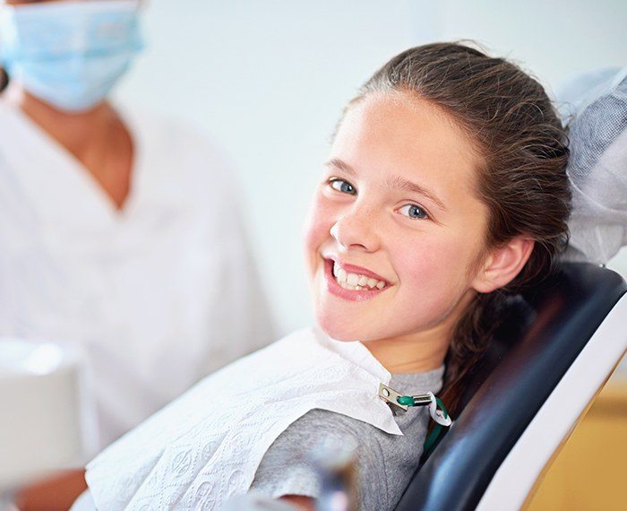 Child in dental chair smiling after silver diamine fluoride