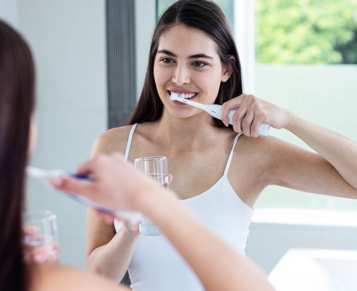 Woman brushing teeth with electric toothbrush