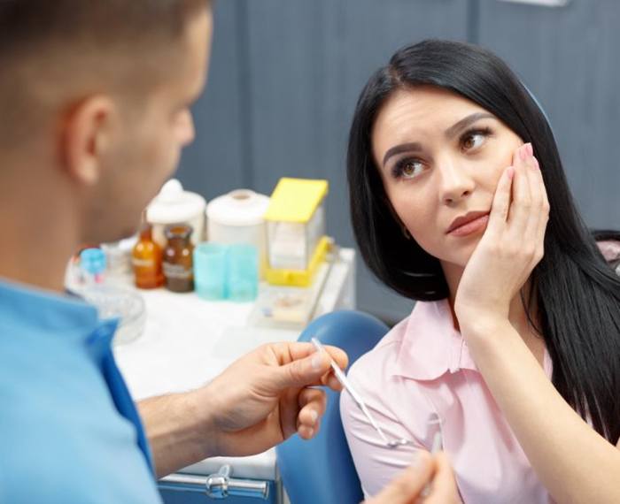 a patient holding her cheek due to tooth pain