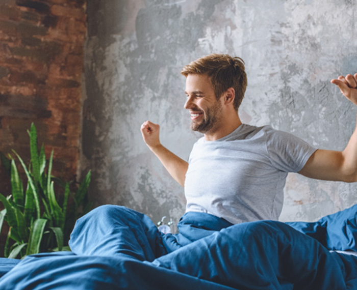 Man waking up refreshed after good night of sleep