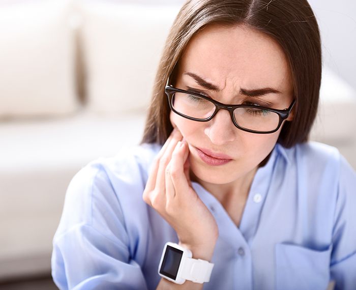 Woman in need of T M J therapy holding jaw