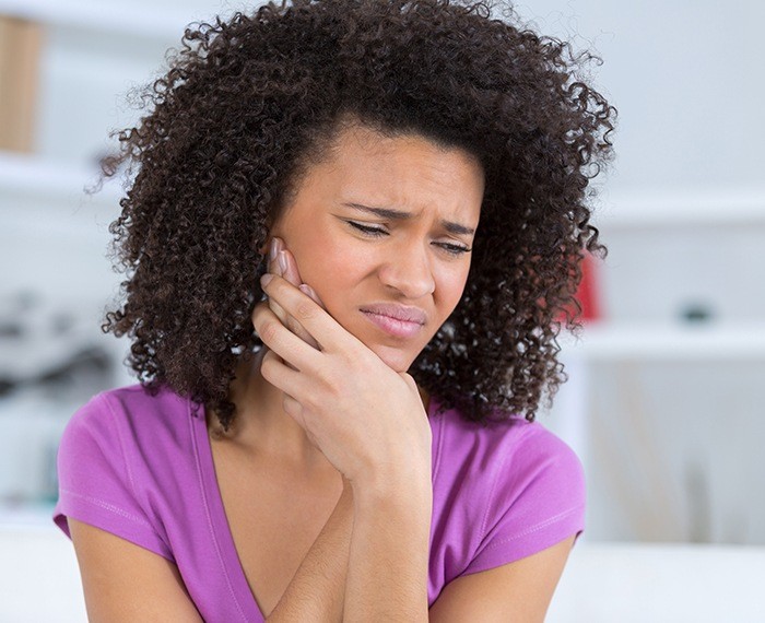 Woman in need of tooth extraction holding jaw in pain