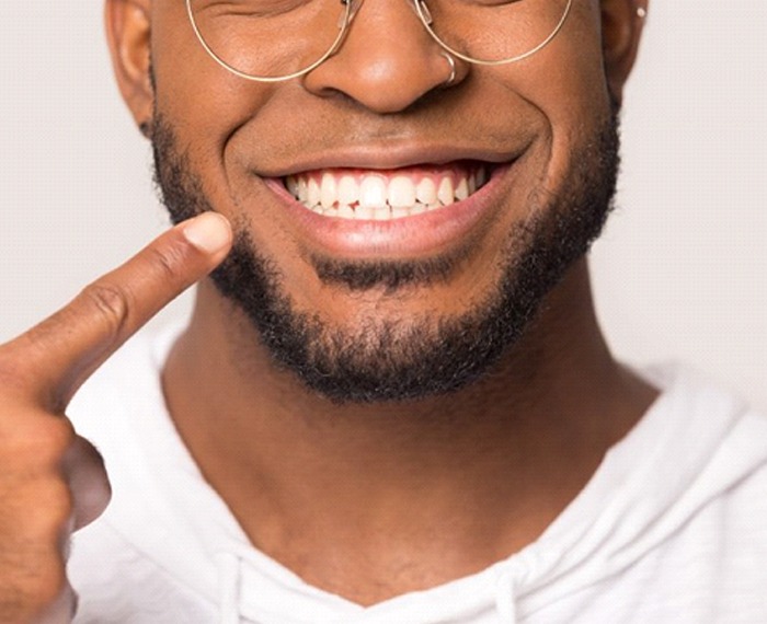 close-up of a man pointing to his smile