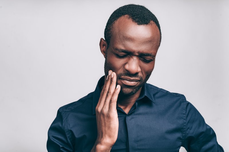 person with tooth pain holding their cheek