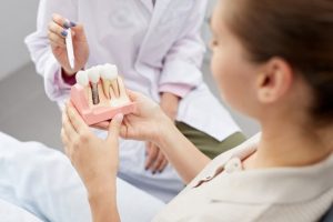 Patient at their dentist’s office holding a model of dental implants.